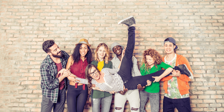 a group of young adults holding up their friend